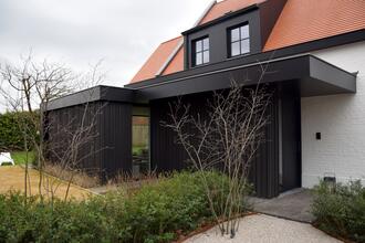 Wit geschilderde gerenoveerde villa met houten zwarte lariks gevelbekleding